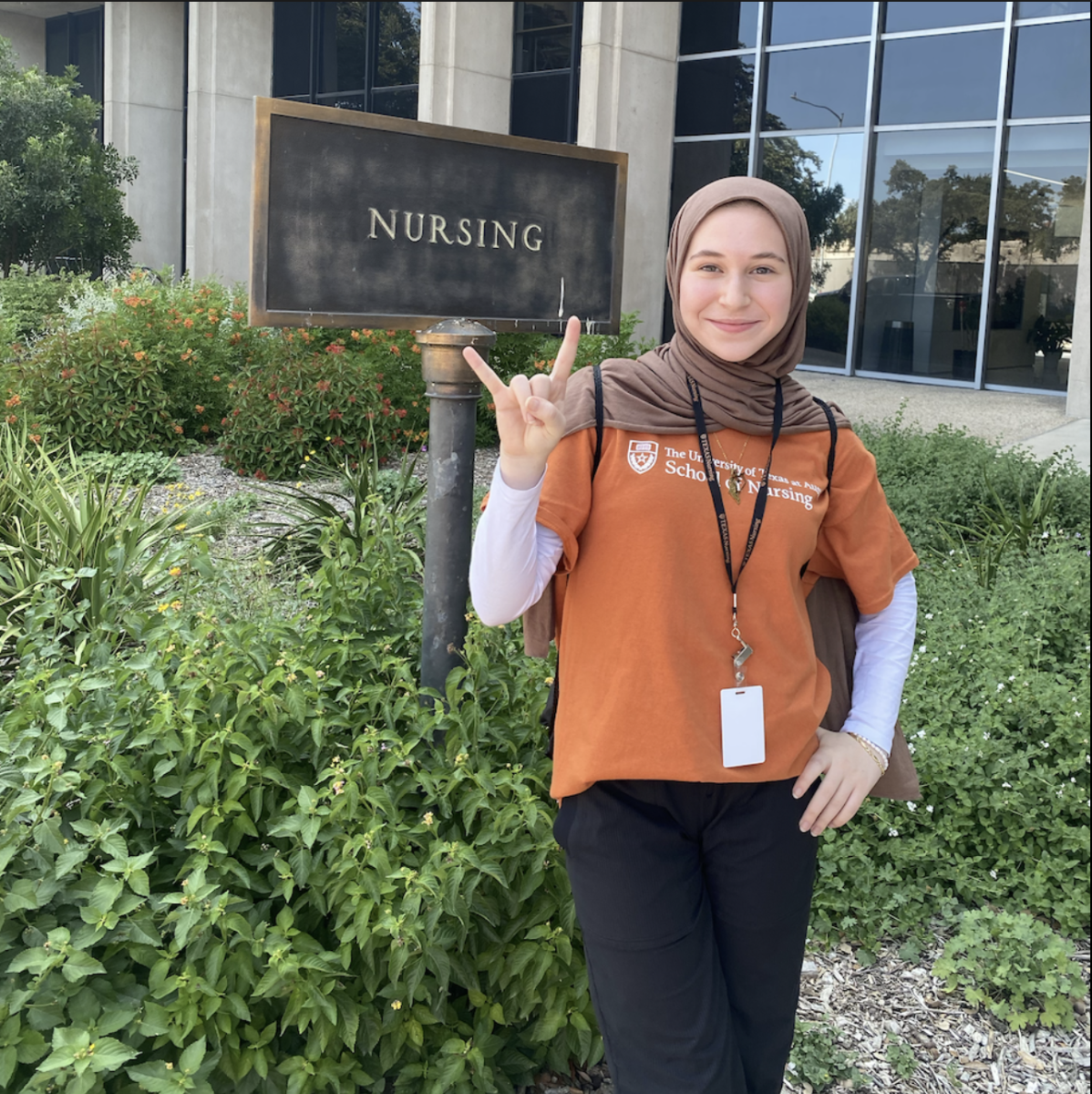 Dana Zohny stands in front of the "Nursing School" sign posted in front of the the School of Nursing building at UT Austin. 